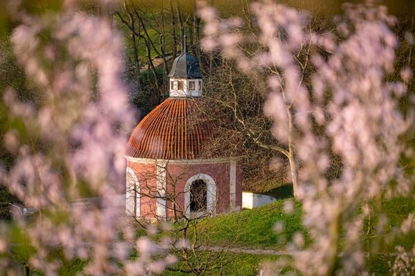 View of the chapel through the branches of blooming trees on Petřín hill