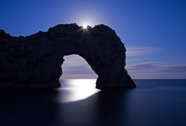 Durdle Door photographed in June as the moon rose over the arch.