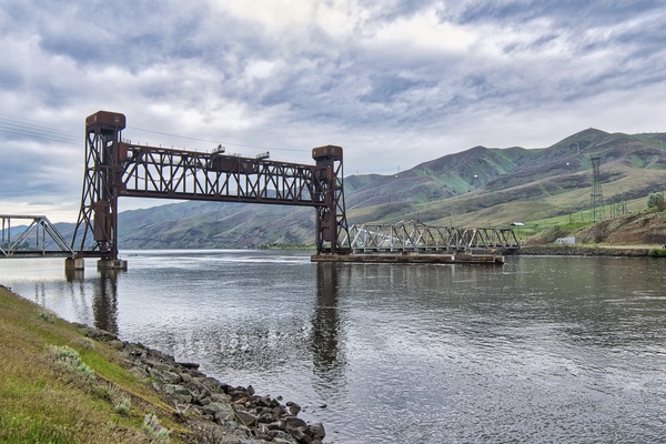 This bridge is a retrofit of an earlier rail crossing before the river was raised by Lower Granite Dam. The original swing draw span was phased out in favor of a new lift span, opening the river to barge traffic. The ports immediately upstream of this bridge make up Idaho's only seaport and allow inland wheat farmers to inexpensively transport their crops down the Snake and Columbia Rivers to the Pacific Ocean.