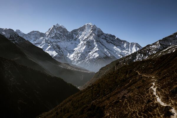 This photo was taken early morning looking back down the valley towards Phortse which you can just see on the left of the photo.  The image doesn't catch the scale of the mountains but if you look carefully, you can see a porter walking up the path on the right carrying a load.  This photo was taken during a 12 day trek in the Everest region.