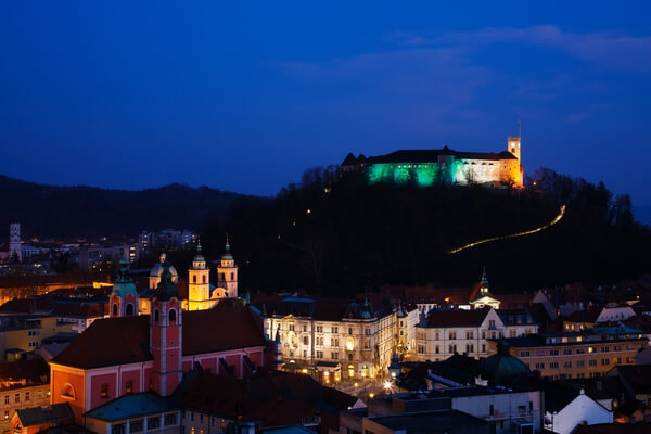 View from Neboticnik at dusk of the Ljubljana Castle lit up in the colours of the Irish flag for Saint Patrick's Day.