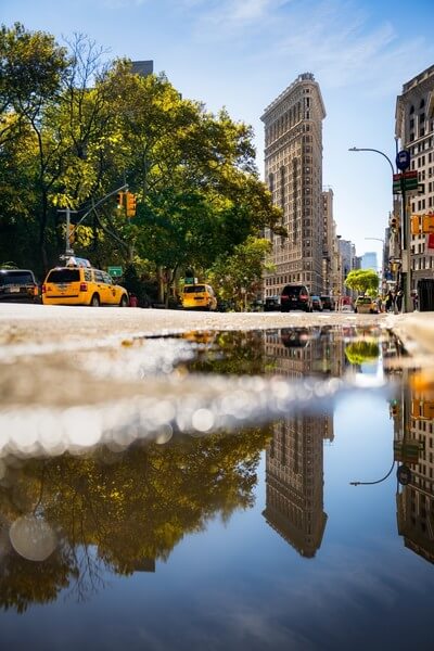 Flatiron Building reflecting in the water puddle