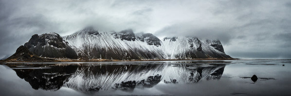 Vestrahorn mountains reflected in the shallow water left by the receding tide