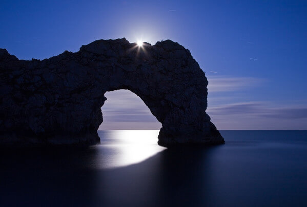 Durdle Door photographed in June as the moon rose over the arch.