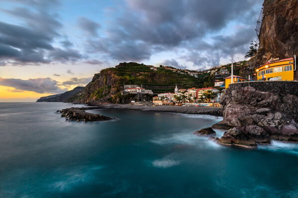 Ponta do Sol, taken with wider angle lens (16mm FF) and several images are blended to get the smooth water with some lights and the best sky from the sunset.