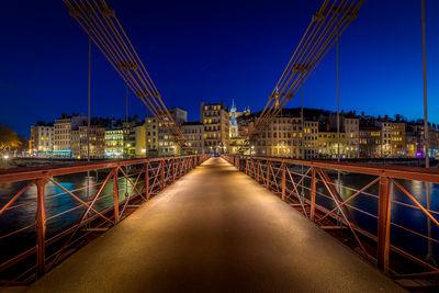 St-Vincent Footbridge on the Saone in Lyon at the blue hour. It is taken from the St-Vincent dock and we can guess on the opposite bank the church of St-Paul of Lyon and at the top of the hill of Fourviere the basilica and the tower.