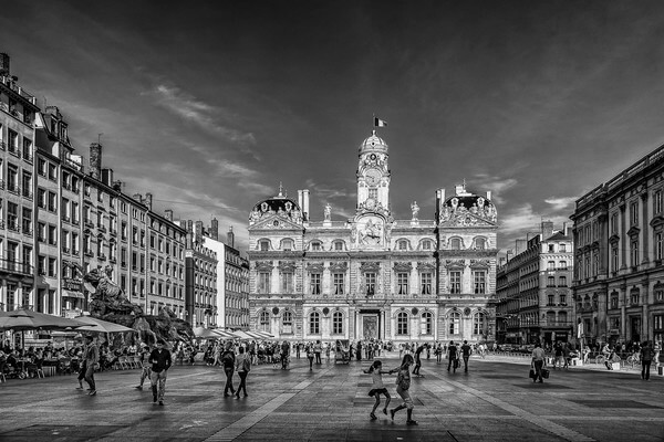 Photo in B/W of the City Hall of Lyon on the square of Terreaux with at the left the Bartholdi Fountain. 
The commonly accepted origin is that the name "Terreaux" comes from the Latin "Terralia" meaning ditch and that a ditch was found here until the sixteenth century. Another origin speaks of the land used to dig these ditches and it is this hillock that would have remained in the memories