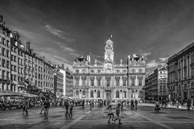 Photo in B/W of the City Hall of Lyon on the square of Terreaux with at the left the Bartholdi Fountain. 
The commonly accepted origin is that the name 
