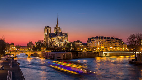 Cathedral Notre Dame of Paris and the Ile de la Cité seen from the Tournelle bridge during the blue hour. On the Seine, a Mouche boat sails. You can also see the Pont de l'Archevéché (on the left) and the Pont St-Louis (on the right).