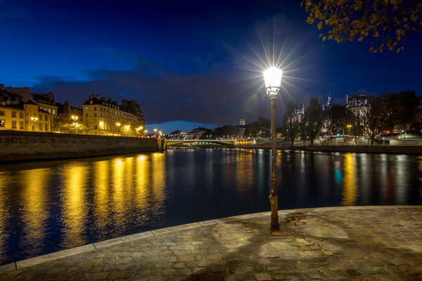 Blue Hour on the Square Louis Aragon at the end of Ile St-Louis in Paris. In the distance, you can see Pont d'Arcole on the Seine, the Paris City Hall, the city Theater, the Chatelet Theater and the Tour Saint-Jacques.