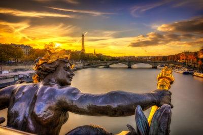 Sunset over the Eiffel Tower seen from the Pont Alexandre III in Paris. In the background, you can also see the Pont des Invalides and the Palais de Chaillot at Trocadero. Copyright Tour Eiffel - illuminations Pierre Bideau