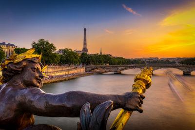 Sunset over the Eiffel Tower seen from the Pont Alexandre III in Paris. In the background, you can also see the Pont des Invalides and the Palais de Chaillot at Trocadero. Copyright Tour Eiffel - illuminations Pierre Bideau