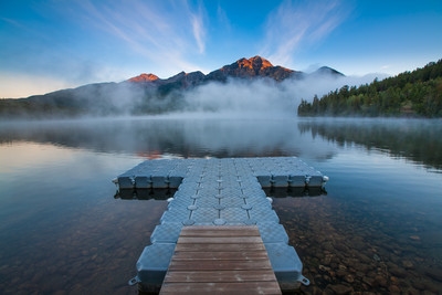 Small floating pier is pointing directly to the Pyramid Mountain. Only mountain peaks are catching the first sun rays. Some morning fog adds to the mystic scenery. Pyramid Lake in Jasper National park at its best.