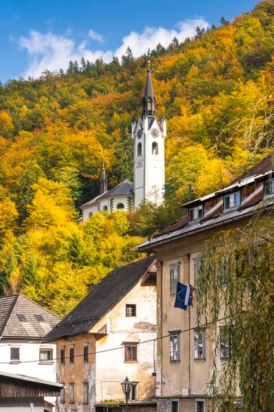 The Church of St.Mary above Kropa town with fall foliage color.