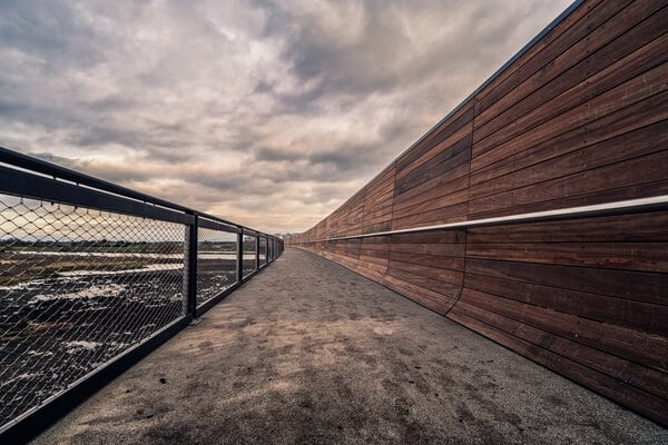 View along the footbridge, showing the interesting wooden wall protecting you from traffic on the bypass.