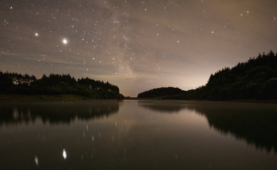 night image looking across the reservoir with jupiter and saturn and the milky way 