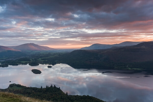 An autumnal sunrise from the summit of Cat Bells looking over a calm Derwent Water.