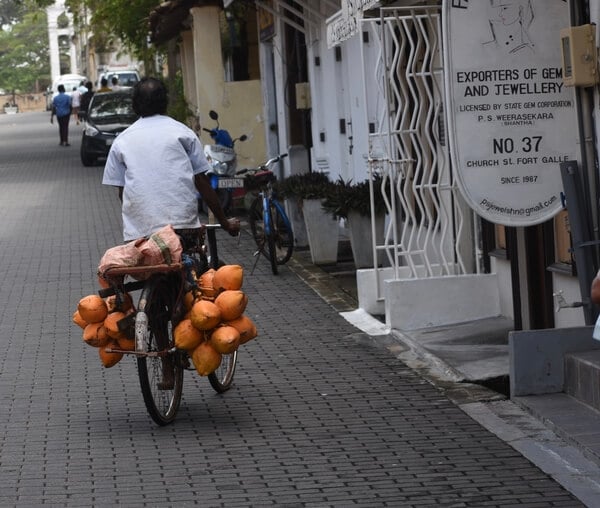 A King Coconut seller in Galle Fort Sri Lanka plying his trade on a bicycle, in the World Heritage Site. 