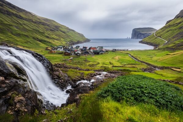 Tjørnuvík with his waterfall located above the town, next to the path.