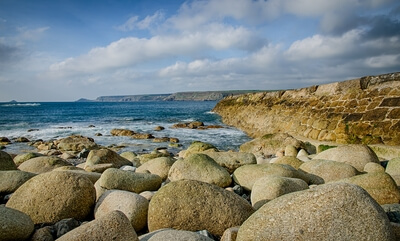 Rounded boulders on the beach next to the harbour wall