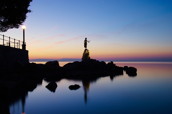 Maiden with seagull (symbol of Opatija) at dawn with Kvarner gulf in the background in winter