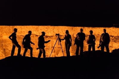 A group of photographers is silhouetted against the crater after dark
