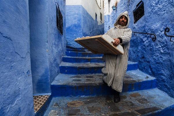 A Man Carries Fresh Baked Goods in a Street in Chefchaouen