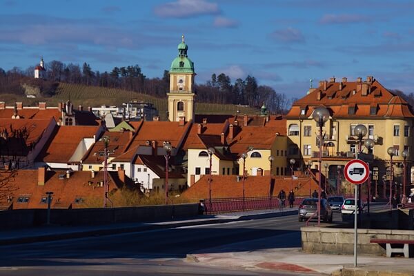 View across Old bridge from right bank to red tiled roofs of houses on Lent, cathedral and Kalvarija hill in the background