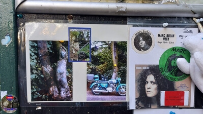 Tribute messages on the 'Memory Board' at Marc Bolan's Rock Shrine, Gipsy Lane, Barnes, SW15 5RG London including two photographs taken by TAG founder taken in June 1978. Photograph taken on the 16th September 2021 - The 44th Anniversary of his passing at this site. Marc's Shrine has been cared for since 1999 by TAG (T.Rex Action Group) via an in-perpetuity lease on the site. The PRS Memorial was installed in September 1997 for the 20th Anniversary. Five years later the bronze bust of Marc Bolan was installed for the 25th Anniversary. Both were unveiled by Marc Bolan's only heir Rolan Bolan who was just 10 days short of his second birthday when his dad died. That fateful night Rolan was asleep at his paternal grandparents home in Putney. Marc and his partner, Rolan's mother were on their way home at 142 Upper Richmond Road West, Sheen.  