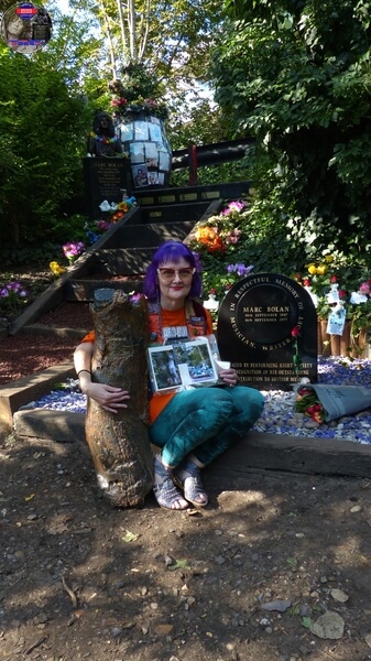 TAG Founder Fee Warner at Marc Bolan's Rock Shrine, Gipsy Lane, Barnes, SW15 5RG London. Photograph taken on the 16th September 2021 - The 44th Anniversary of his passing at this site. Marc's Shrine has been cared for since 1999 by TAG (T.Rex Action Group) via an in-perpetuity lease on the site. The PRS Memorial was installed in September 1997 for the 20th Anniversary. Five years later the bronze bust of Marc Bolan was installed for the 25th Anniversary. Both were unveiled by Marc Bolan's only heir Rolan Bolan who was just 10 days short of his second birthday when his dad died. That fateful night Rolan was asleep at his paternal grandparents home in Putney. Marc and his partner, Rolan's mother were on their way home at 142 Upper Richmond Road West, Sheen.  