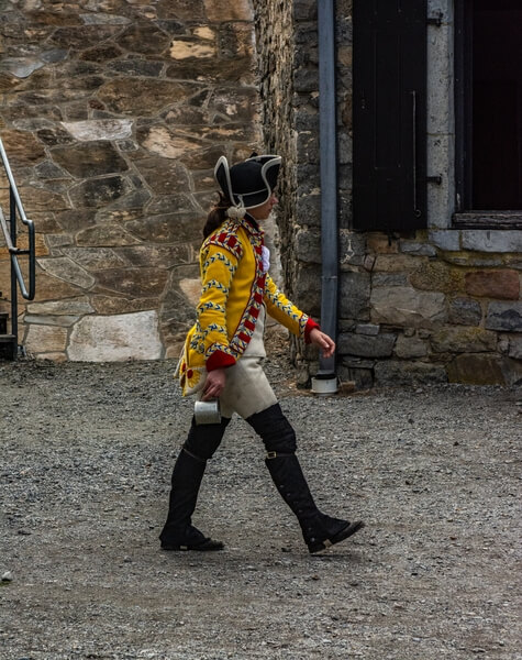 Reenactor in the uniform of a musician in the British 26th Regiment of Foot.  The uniform of a line soldier in the 26th was red with yellow trim for cuffs and lapel facings.  Musicians wore yellow uniforms with red trim and blue highlights.
