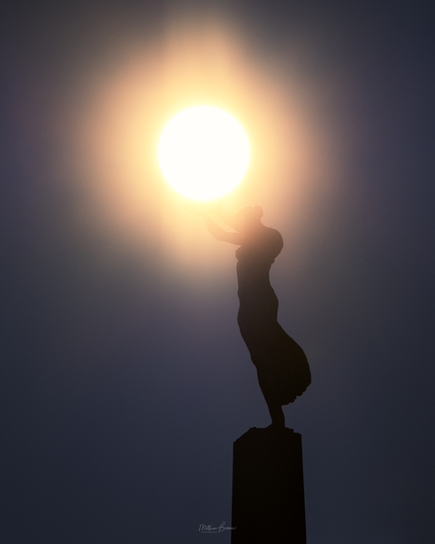 With a telephoto you can create the illusion she is holding the sun