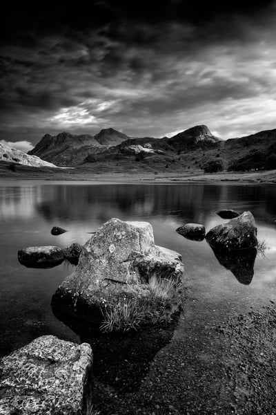 Early morning shot of Blea Tarn from the southern shoreline. There are some interesting boulders to make good foreground and lack of wind makes a good reflection. The black and white interpretation adds to the tranquility of that moment.