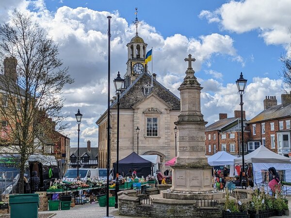 Market day in Brackley with the Town Hall in the background. In the foreground is the war memorial