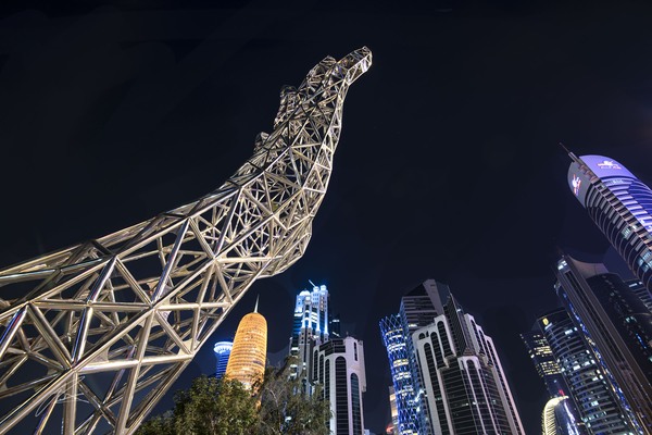 Hand sculpture reaching to the night skyline along the Corniche, Doha Qatar