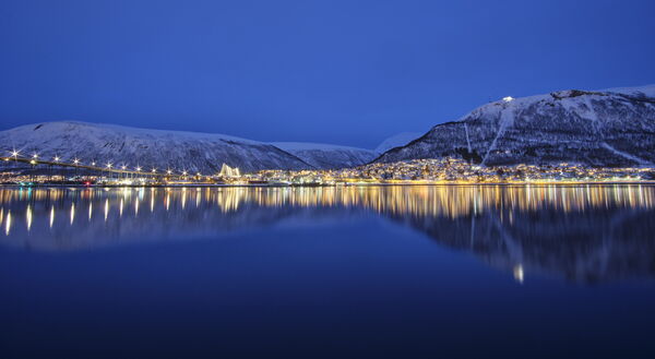 The view from Tromsø marina with Tromsø Bridge, the Arctic Cathedral and Fjellheisen cable car during the blue hour.