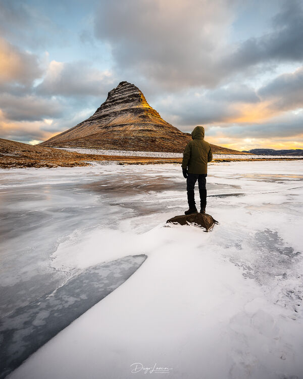 I'm here, in front of Kirkjufell mountain in Iceland, while the sun is rising and the clouds are turning orange