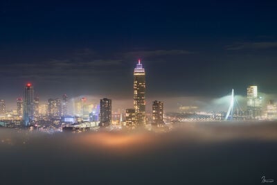 The Erasmus bridge and the newly build Zalmtoren during evening, with fog drifting in.