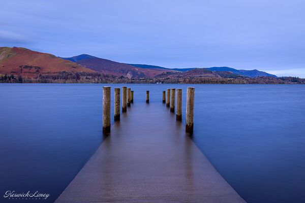 View from Ashness Gate Landing Stage at sunrise with the lake lapping over the jetty.