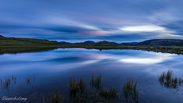 Tewet Tarn at sunset with reflections of the sky.