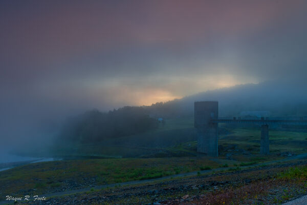Sunrise obscured by fog. Gatehouse in the foreground.