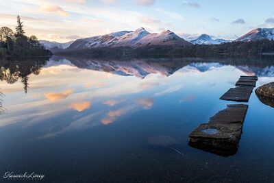 A mid-winter sunrise with snow capped mountains and the jetty exposed.