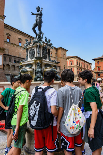 Teenagers filling up their water bottles at an old-style water fountain.