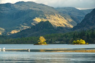The late evening sun is catching the two small islands and also shining behind High Spy to light up the Borrowdale Fells