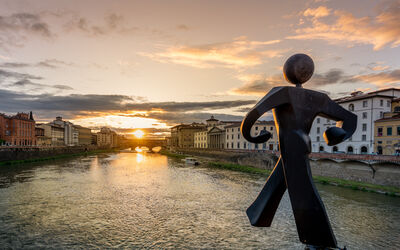 The Walking Man statue at sunset, towards Ponte Vecchio