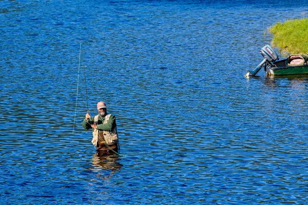 Fisherman with a trout on the line.