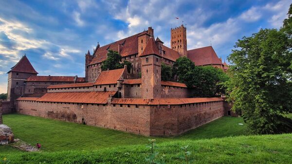Malbork Castle is a stunning photography location that offers a wealth of opportunities for capturing beautiful images. Here's a description of the exterior and walls of the castle:The castle walls: The exterior view of the castle walls is a sight to behold. The walls are made of red brick and are several meters high, with towers and turrets that provide a dramatic backdrop for photography