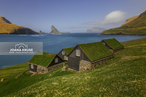 Turfed Houses and sea stack Tindholmur in Bour, Faroe Islands