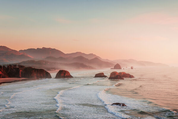 A pastel sunset from Ecola State Park with Haystack Rock off in the distance
