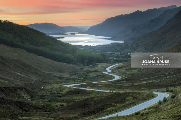 A winding road snaking through majestic Munros, leading to the shimmering expanse of Loch Maree.

